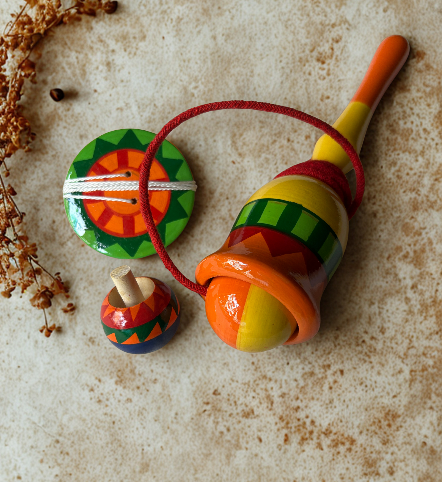 Colorful wooden top and spinner and cup and ball on a textured surface