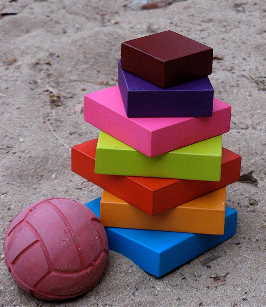 Stack of colorful wooden blocks on a sandy terrain
